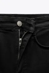 Jeans skinny de tiro alto en denim azul oscuro, con cinco bolsillos y cierre frontal con cremallera y botón metálico.
