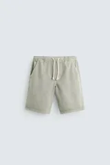 Bermuda relaxed fit confeccionada en denim de algodón color verde oliva. Cintura elástica ajustable con cordón. Bolsillos frontales y detalle de bolsillos traseros de vivo.
