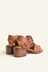 Sandalia de cuero vacuno texturado color negro, con tiras anchas y hebilla lateral. Taco ancho de madera.