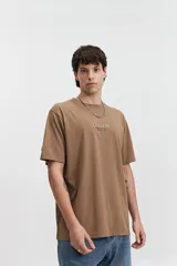 Remera marrón de manga corta con cuello redondo y estampado en la espalda con motivos geométricos y el logo de la marca Mistral.