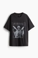 Remera negra de corte oversized con estampado del logo de la banda de rock Evanescence y una imagen de un ángel. Cuello redondo ribeteado y hombros caídos.
