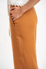 Pantalón de lino color ocre, de corte recto y tiro medio, con lazo de ajuste en la cintura.