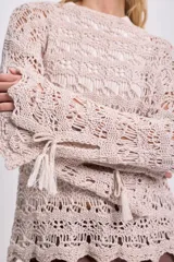 Buzo de punto calado color beige, de mangas largas y cuello redondo.