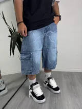 Bermuda de jean celeste con estampado de rayos blancos, corte holgado y bolsillos cargo.