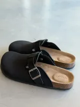 Zuecos negros con hebilla plateada ajustable y plantilla anatómica de corcho.