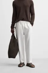 Pantalón de lino color marrón oscuro, de corte recto y relaxed fit. Tiene cintura elástica ajustable con cordón, bolsillos frontales y traseros de parche.