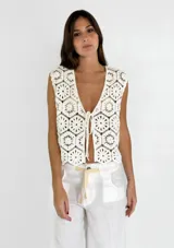 Chaleco blanco de crochet con escote en V y lazos para atar en el frente.