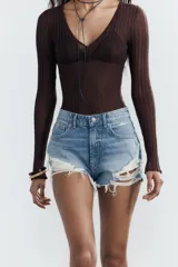 Shorts de denim negro con tiro medio, cinco bolsillos y efecto desgastado con roturas pronunciadas y bajo deshilachado.