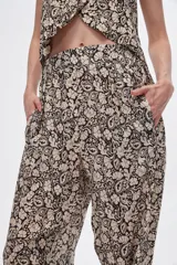 Pantalón slouchy de viscosa con estampado floral en tonos beige y negro, bolsillos laterales, cintura alta y detalle de punto smock en los tobillos.