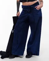 Pantalón de denim azul intenso, corte sastrero de pierna ancha, tiro alto o a la cadera (según el talle elegido), cierre frontal invisible, pretina cruzada y bordado negro del logo Temblad en la parte trasera.
