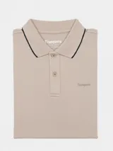 Remera tipo polo color beige, de corte clásico, con cuello y puños acanalados en contraste marrón oscuro.