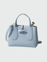 Bolso Longchamp modelo Le Roseau, color celeste, con doble asa corta, cierre con broche metálico y detalles de cuero.