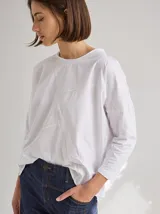 Remera blanca de algodón con corte holgado y costuras a la vista en color beige.