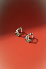 Aros plateados con diseño orgánico y texturizado, simulando metal arrugado o fundido, con forma de argolla abierta.