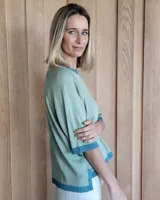 Buzo de punto color verde kiwi con cuello, puños y ruedo en azul.