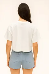 Remera cropped de algodón color crudo, con cuello redondo y estampado abstracto en el frente.