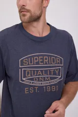 Camiseta azul marino de manga corta y cuello redondo con estampado frontal en color dorado que dice 'Superior Quality D.N.M. Jack & Jones Denim Company Est. 1990'.