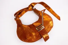 Cartera bandolera de cuero color verde oliva con efecto desgastado. Tiene forma de media luna, asa larga regulable, cierre superior con cremallera y broche imán metálico.