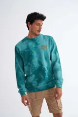 Buzo color turquesa con efecto tie-dye, con estampado en el pecho y diseño de felpa sin friza.