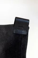 Bota negra de cuero con caña alta y detalle de cobertura de gamuza negra en la parte superior.