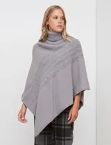 Poncho tejido color negro, con cuello polera y diseño de trenzas diagonales en el frente. Presenta un corte asimétrico en el ruedo.
