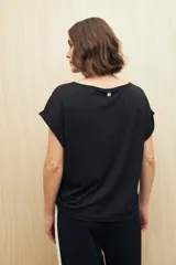 Remera color beige de tejido acanalado, con cuello bote y mangas cortas con dobladillo.