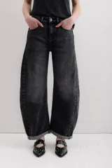 Pantalón de jean negro con corte amplio y ruedo doblado.
