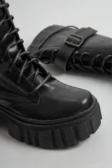 Borcegos negros de ecocuero con cordones de cuerina, caña media y suela track.