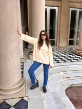 Canguro de paño color crema, de corte holgado y cuello redondo, con puños y ruedo acanalados.