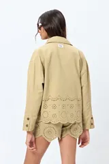 Sobrecamisa blanca de algodón con cuello camisero, botones marrones y detalles de encaje calado en el ruedo.