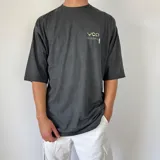 Remera gris con efecto gastado y estampado en la espalda con diseño abstracto en tonos verdes y blancos.