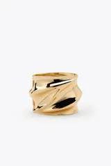 Brazalete rígido dorado con diseño de ondas en relieve.