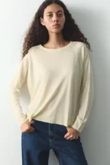 Jersey de punto color verde oliva, con cuello redondo y manga larga. Tiene bajo con aberturas laterales y acabados en rib.