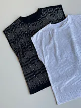 Remera blanca de algodón con cuello redondo y mangas cortas con strass plateado formando líneas verticales.
