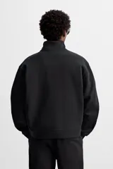 Sudadera negra de algodón con cuello alto y cierre de cremallera frontal. Corte relaxed fit, manga larga y terminaciones en rib.
