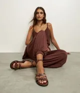 Sandalias planas de cuero color marrón, con múltiples tiras finas ajustables con hebillas doradas. Tira que se ata al tobillo.