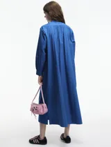 Vestido largo azul de algodón, con cuello mao, mangas largas y corte evasé. Presenta pechera con botones y bolsillos laterales. Ideal para uso casual en verano.