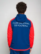 Campera deportiva con capucha, azul con mangas y hombros rojos, cierre frontal y escudo del Club Nacional de Football en el pecho.