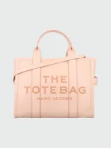Bolso tote de cuero negro Marc Jacobs, tamaño mediano, con doble asa corta y correa larga extraíble. Estampado frontal con el texto "THE TOTE BAG" y el nombre de la marca.