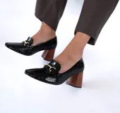 Zapato tipo mocasín de charol negro, con taco de 7 cm y suela acolchada.