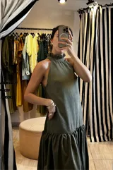 Vestido largo verde oliva de tela simil agamuzada, con escote halter, espalda baja y volados en cuello y cadera.