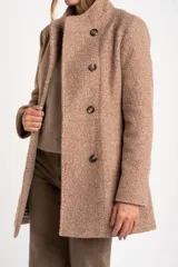 Tapado de poliéster con textura en color beige, de calce al cuerpo. Cuenta con cuello alto, cierre frontal de botones oscuros y bolsillos laterales.