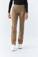 Pantalón de vestir color café con corte recto, tiro alto y elástico en la cintura. Presenta bolsillos laterales y detalle de cuero en los laterales.