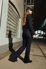 Jeans de cinco bolsillos en denim azul marino con leve stretch. Diseño de raya diplomática con hilos brillantes en la trama. Corte ajustado de cintura a cadera y acampanado desde la rodilla al bajo. Modelo de tiro bajo con cierre y botón.