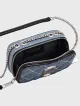 Bandolera Marc Jacobs modelo The Quilted Denim Softshot, confeccionada en denim azul acolchado con patrón de rombos. Presenta el logo Double J en metal plateado, correa de cuero y cadena, y cierre de cremallera doble.