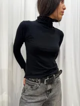 Polera blanca de algodón con cuello alto y mangas largas.