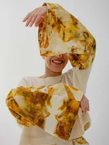 Buzo color crudo con mangas largas acampanadas con estampado floral en tonos amarillos y marrones.