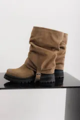 Bota de caña media color marrón claro, de gamuza con efecto arrugado, suela track y detalle de tira lateral con hebilla.