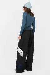 Pantalón deportivo gris de nylon, de calce recto y tiro medio, con elástico en la cintura, cordones ajustables y detalle de recorte con vivo a contratono en los laterales.