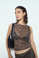 Top sin mangas ajustado al cuerpo, color negro, con estampado animal print abstracto en tonos marrones y negros. Presenta un escote cerrado y es de tejido traslúcido.